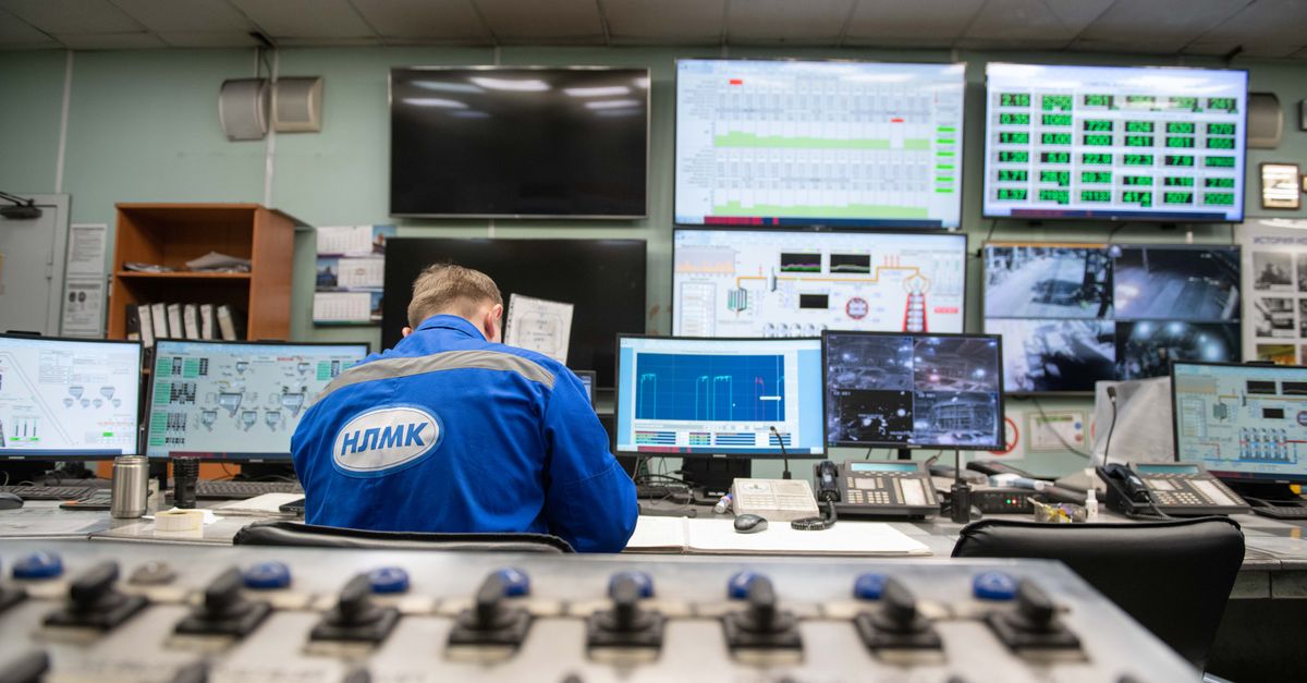 Operador de mesa de trading observando varias pantallas con datos en una sala con luz azul
