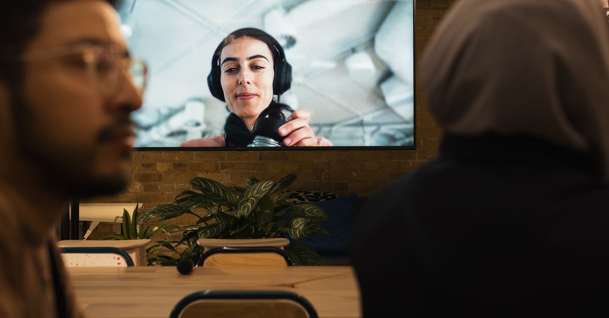 Persona con auriculares frente a una pantalla con gráficos de audio en tonos azules